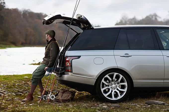Man with fishing gear standing behind his car