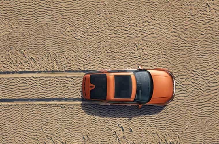 Orange Range Rover driving through sand